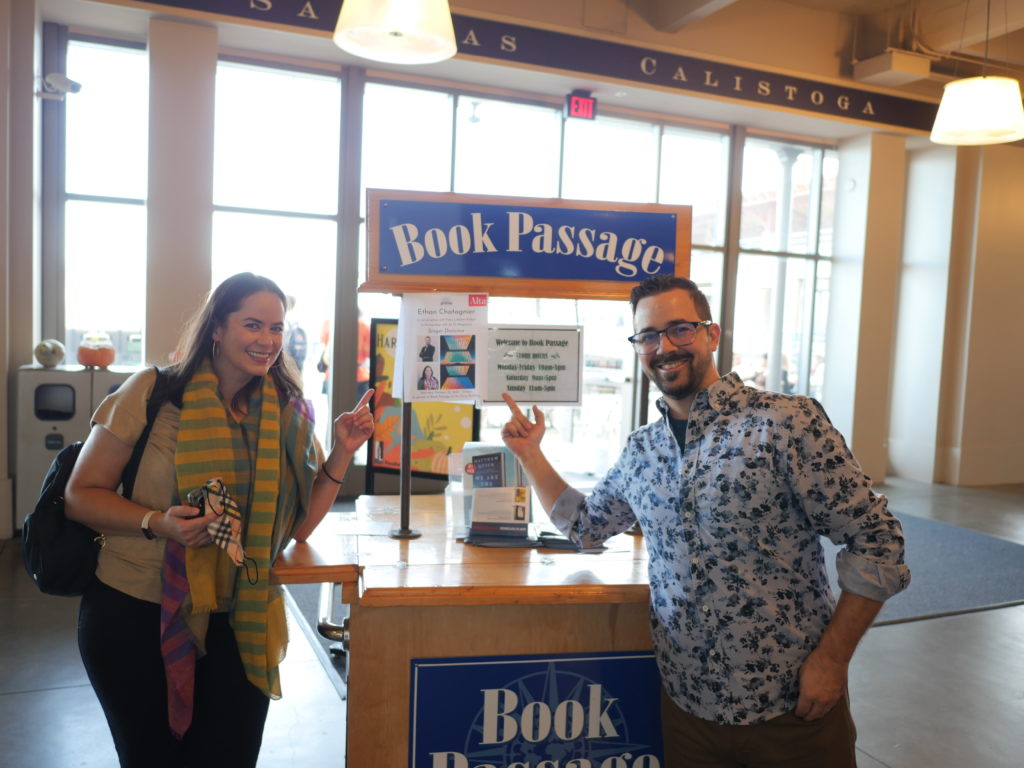 Talia and Ethan Chatagnier stand outside Book Passage. They are pointing to a sign about their event.